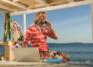 surf man on phone and laptop at beach